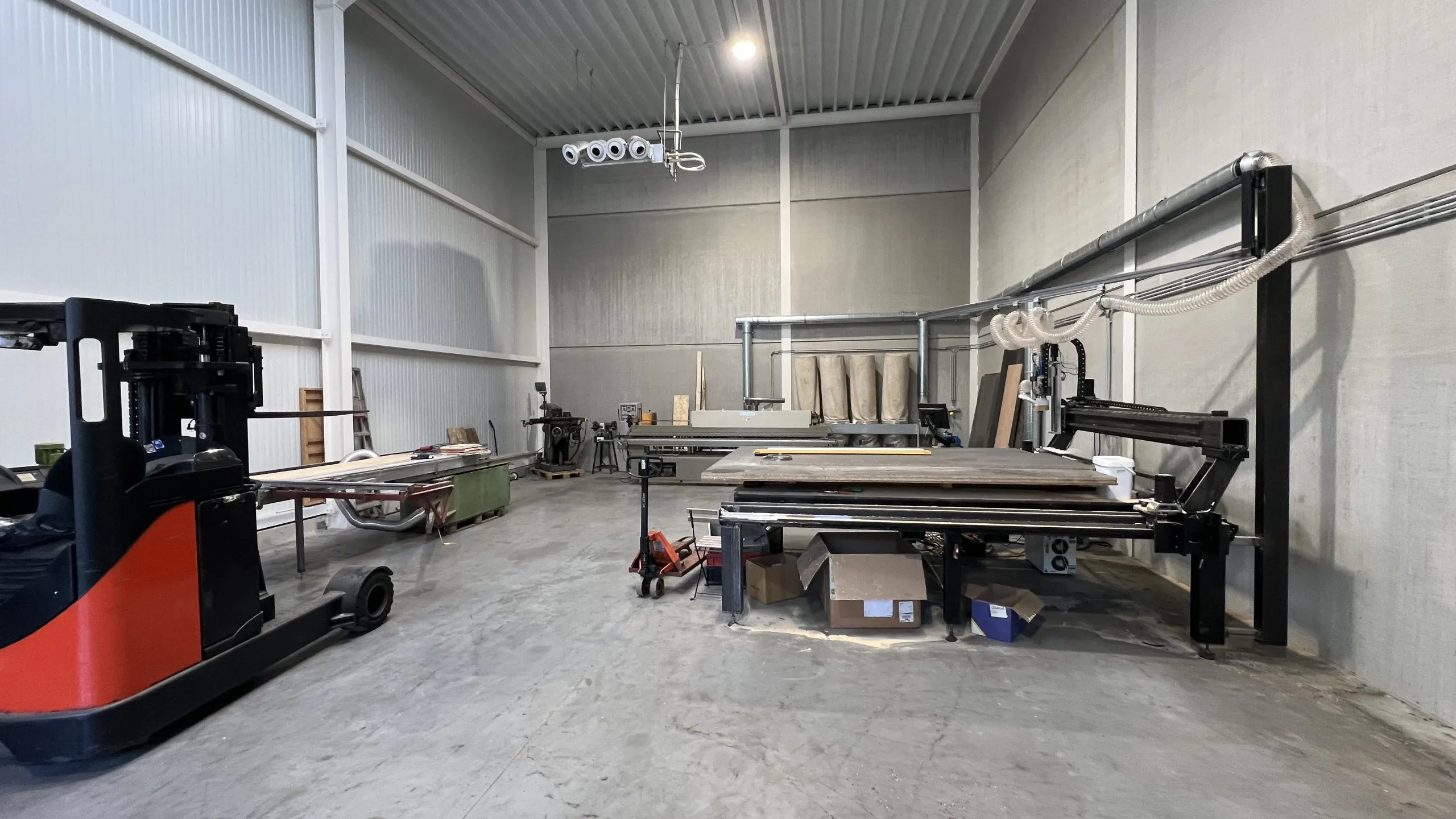 Het atelier van Gila Interieur met de grootformaat CNC-machine centraal en plaatmateriaal opgesteld langs de wand